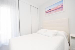 um quarto branco com uma cama e um quadro na parede em Cubo's Apartamento Tivoli B4 em Benalmádena