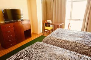 a hotel room with two beds and a flat screen tv at Almudena Suites Uyuni in Uyuni