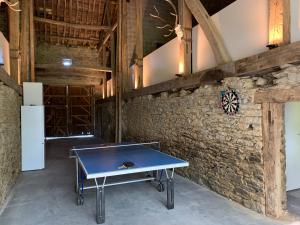 a ping pong table in a room with a brick wall at La Ferme du Grand Frêne in Naomé