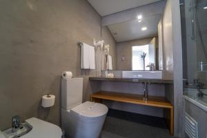 a bathroom with a toilet and a sink and a mirror at Agua d'Alma Hotel in Foz do Arelho