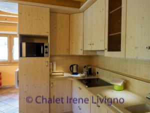 リヴィーニョにあるChalet Irene Livignoのキッチン(木製キャビネット、電子レンジ付)