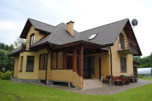 a yellow house with a black roof and a table at Dom Gościnny in Polańczyk