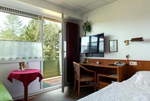 Schlafzimmer mit einem Schreibtisch, einem Bett und einem Fenster in der Unterkunft Hotel Schleifmühle in Holzminden