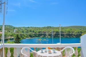 a table and chairs on a balcony with a view of a river at Apartmani Mirko A1 in Molat