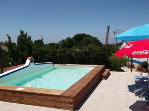 a pool with a wooden deck and an umbrella at Quinta do Pinheiro in Grândola