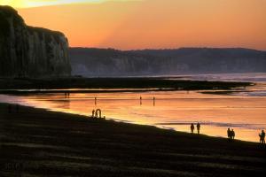 a group of people walking on the beach at sunset at Smile in Dieppe