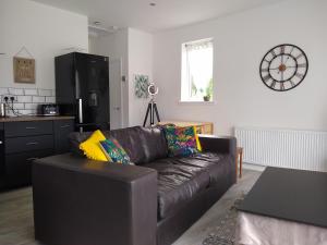 a living room with a brown leather couch and a kitchen at Taigh Na Frithe in Fort Augustus
