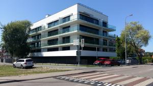 a white building with cars parked in front of it at Hel Amber Apart in Hel