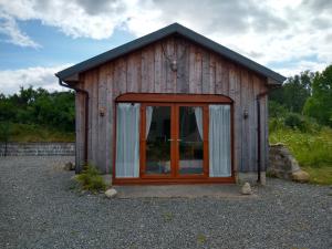 a small wooden house with a large glass door at Taigh Na Frithe in Fort Augustus