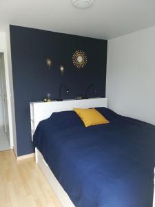 a bedroom with a blue bed with a yellow pillow at Vie de famille in Sainte-Cécile-Plage +16 photos
