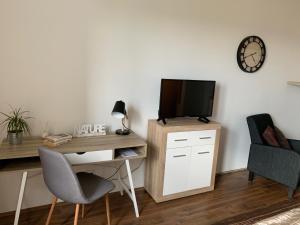 a room with a desk with a tv and a chair at Liliom Apartman Pécs in Pécs