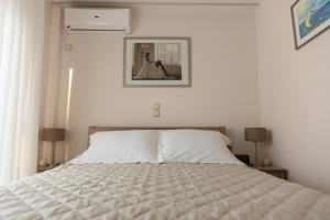 uma cama branca num quarto branco com 2 candeeiros em ivannas penthouse em Atenas
