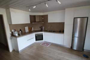 uma cozinha com armários brancos e um frigorífico de aço inoxidável em Les Narcisses em Blonay