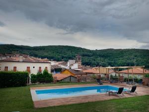 a villa with a swimming pool in front of a town at Hotel Rural La Casa De Pasarón in Pasarón