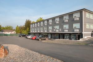Un gran edificio con coches aparcados en un estacionamiento. en Days Inn by Wyndham 100 Mile House, en One Hundred Mile House