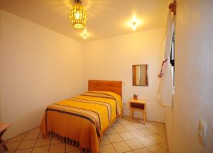 a bedroom with a bed with a yellow blanket at Casa Gecko in Oaxaca City