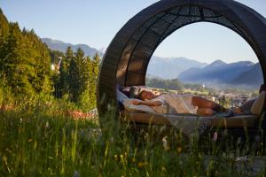 a woman laying in a swing bed in a field at Das Kaltenbach - ApartHotel in Kaltenbach