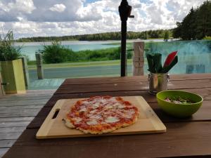 a pizza on a wooden cutting board on a table at North Lakeside B&B Plateliai in Plateliai