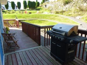 a grill on a deck with a chair and a lawn at Pioneer Inns in Prince Rupert