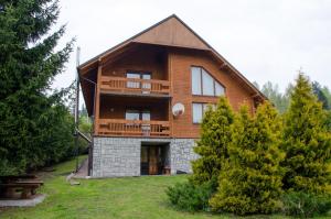 uma grande casa de madeira com uma varanda no quintal em Zrub em Skhidnitsa