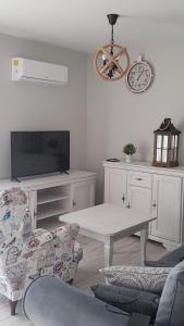 - un salon blanc avec une table et une télévision dans l'établissement Apartament Homole E2 Szczawnica, à Szczawnica