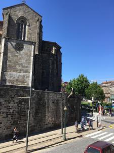 um antigo edifício de tijolos com uma torre de relógio numa rua em Pimms Home Ribeira em Porto