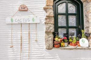 a sign on the side of a building with potted plants at ''Cactus'' Traditional house in Vólax