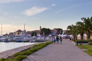 eine Gruppe von Menschen, die einen Bürgersteig neben einem Hafen entlang laufen in der Unterkunft Apartman Zorica in Biograd na Moru