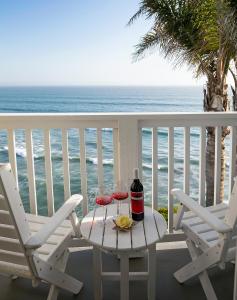 a table with two wine glasses on a balcony with the ocean at Pismo Lighthouse Suites in Pismo Beach