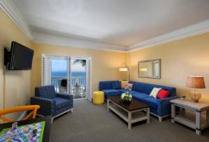 sala de estar con sofá azul y sillas en Pismo Lighthouse Suites en Pismo Beach