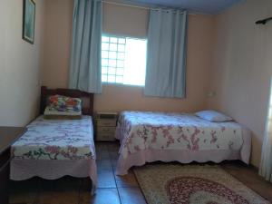 1 dormitorio con 2 camas y ventana en Recanto Flor de lis en Gonçalves
