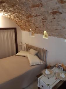 una camera con letto e parete in pietra di Donna Lucrezia dimora a corte B&B a Conversano