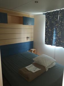 Schlafzimmer mit einem Bett mit einem Kissen und einem Fenster in der Unterkunft Mobil home climatisé en Alsace in Biesheim