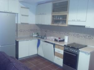 eine Küche mit weißen Schränken und einem schwarzen Gerät in der Unterkunft Rafto Apartment in Ohrid