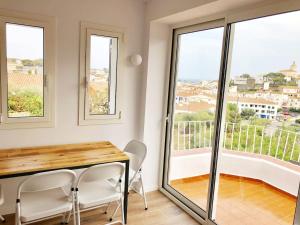 comedor con mesa, sillas y ventanas en Ses Terrasses en Cadaqués
