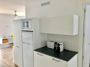 a white kitchen with a refrigerator and a microwave at Ses Terrasses in Cadaqués