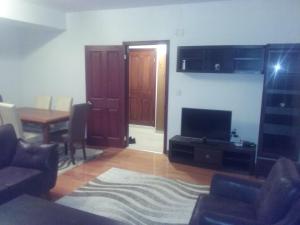 ein Wohnzimmer mit einem TV und einem Tisch mit Stühlen in der Unterkunft Rafto Apartment in Ohrid