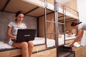 a woman sitting on a bunk bed with a laptop at Hostel Center in Ulcinj