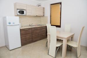 ラブダにあるApart Levのキッチン(木製テーブル、白い冷蔵庫付)