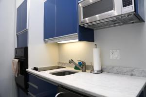 a kitchen with blue cabinets and a sink and a microwave at Large Stylish Newbury Street Studio w/ Kitchen in Boston