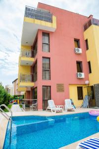 a building with a swimming pool in front of a building at Apart Lev in Ravda