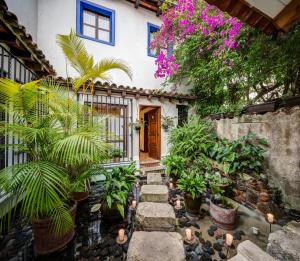 um jardim com plantas em frente a uma casa em Casa Encantada by Porta Hotels em Antigua Guatemala