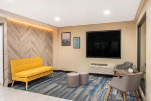 Budget Inn في ميرسيد: غرفة انتظار مع أريكة صفراء وتلفزيون