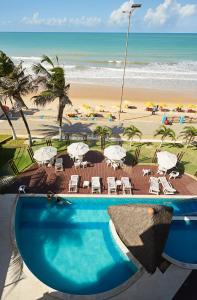 una piscina junto a una playa con sillas y sombrillas en Elegance Coberturas Vip Beira Mar, en Natal