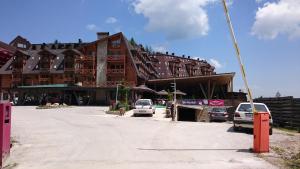 a large building with cars parked in front of it at Apartman Lukas privatni app u sklopu aparthotela Vučko in Jahorina +5 photos