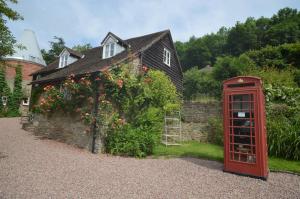 een rode telefooncel voor een huis met bloemen bij Whitewells Farm Cottages in Great Malvern