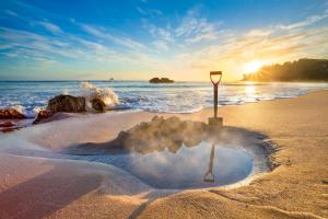 a ball of steam on the beach with a sign in the sand at Hot Water Beach Bure Wai in Hotwater Beach