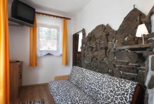 sala de estar con pared de piedra y sofá en Pokoje Oko en Zakopane