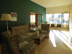 a living room with a couch and chairs and a table at Hotel Oviedo in Río Gallegos