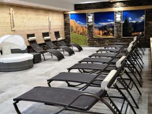 une rangée de chaises dans une salle d'attente avec des affiches dans l'établissement Apart Hotel Ideal, à Ladis